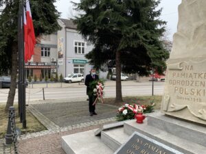 Biało-czerwone kwiaty przed pomnikiem odrodzenia Polski składa Prezes Zarządu Kopalni Soli "Wieliczka" Trasa Turystyczna Michał Roehlich