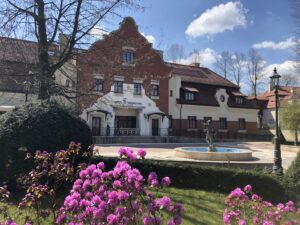 Front - Hotel Grand Sal.  Długi budynek częściowo z cegły. Za pierwszym planie kwitnące na fioletowo krzewy