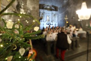 Górnicza Pasterka. Po lewej stronie kadru choinka, w głębi, nieostry ołtarz główny i dziecięcy chór