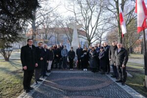 Pamiątkowa fotografia uczestników uroczystości. W tle pomnik z orłem oraz Zamek Żupny