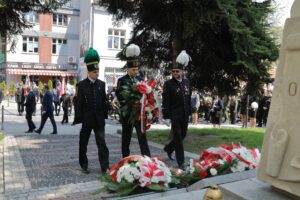 Przedstawiciele Kopalni Soli "Wieliczka" S.A. składają biała-czerwone kwiaty. Trzech górników w galowych mundurach