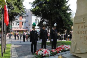 Reprezentacja Kopalni Soli "Wieliczka" przy pomniku poległych za Ojczyznę wieliczan. Po prawej stronie kadru widoczny fragment postumentu z częścią złoconego napisu