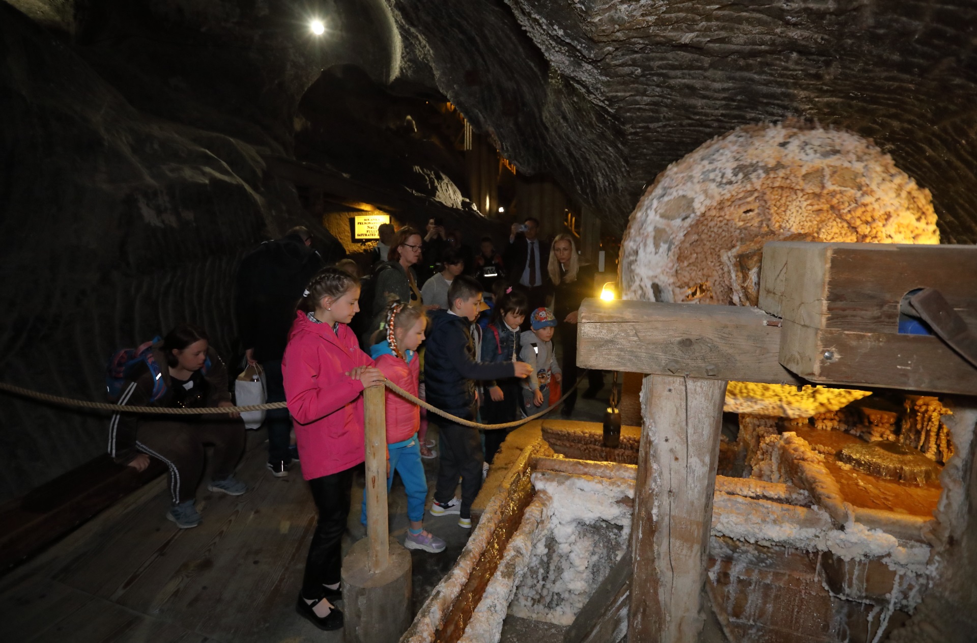Rodziny zastępcze zwiedzają kopalnię. Dzieci oglądają drewnianą pompę pater noster