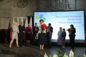 Minister Marlena Maląg z pamiątkową statuetka oraz bukietem kwiatów