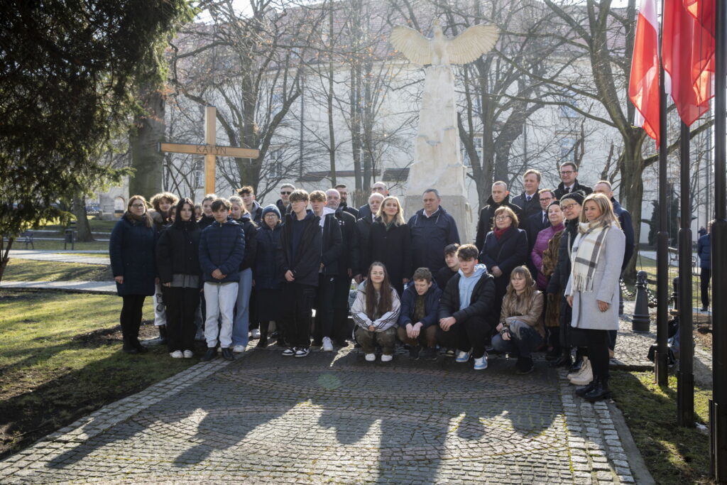 Uczestnicy uroczystości na tle Pomnika Niepodległości. Zdjęcie grupowe, w tle obelisk z rzeźbą przedstawiającą orła