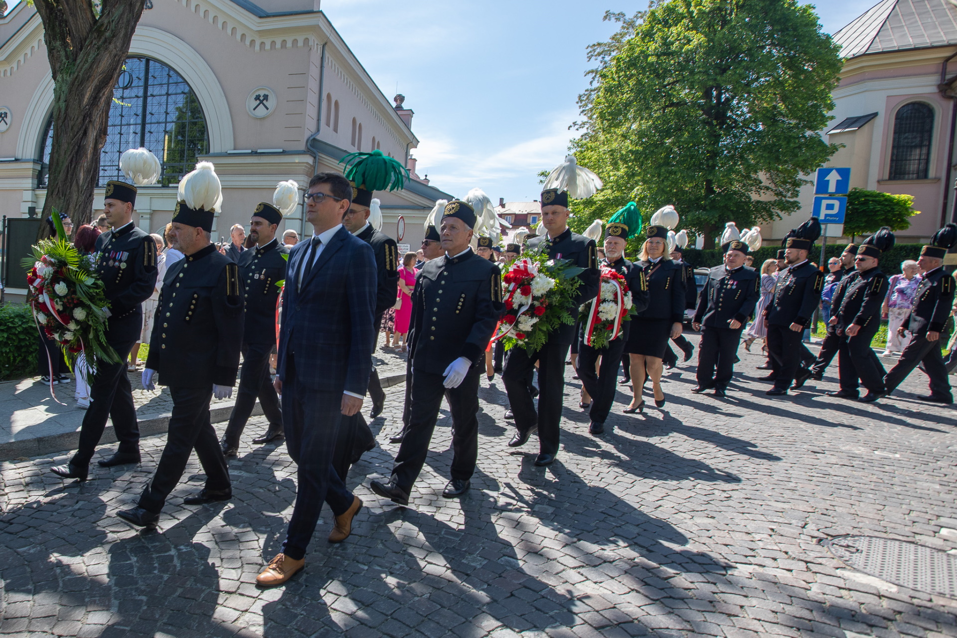 Górnicy w galowych mundurach na ulicach Wieliczki. W tle budynek szybu Regis