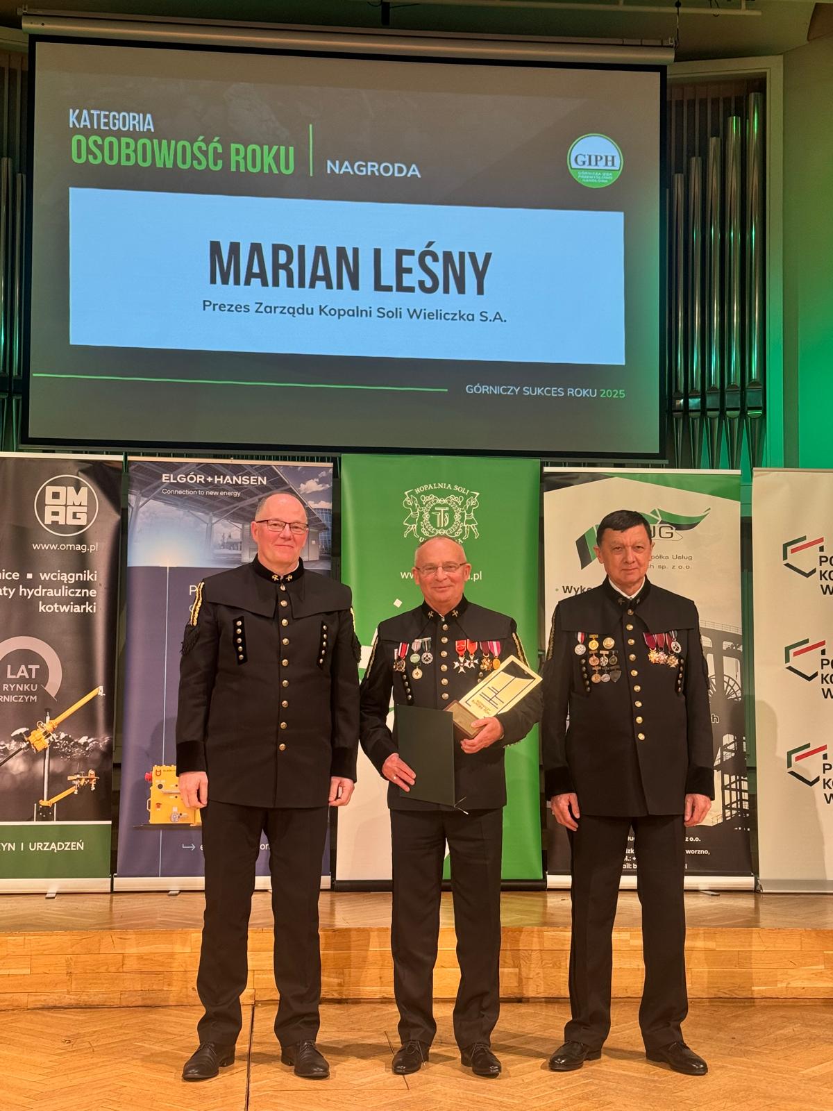 Prezes Marian Leśny na scenie w Filharmonii Śląskiej. Ubrany w galowy mundur górniczy prezentuje nagrodę Osobowość Roku