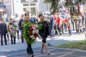 Dwuosobowa delegacja składa biało-czerwone kwiaty. Po prawej pani prezes Barbara Ptak, po lewej członek zarządu Mariusz Kot