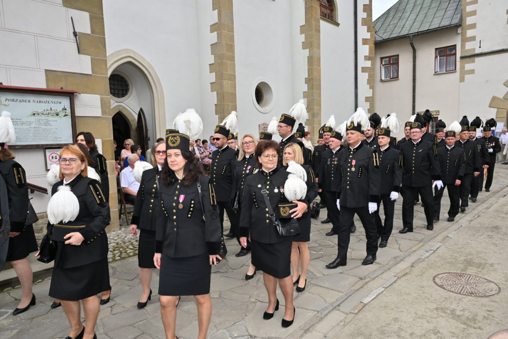 Górnicy w galowych mundurach wchodzą na dziedziniec klasztoru