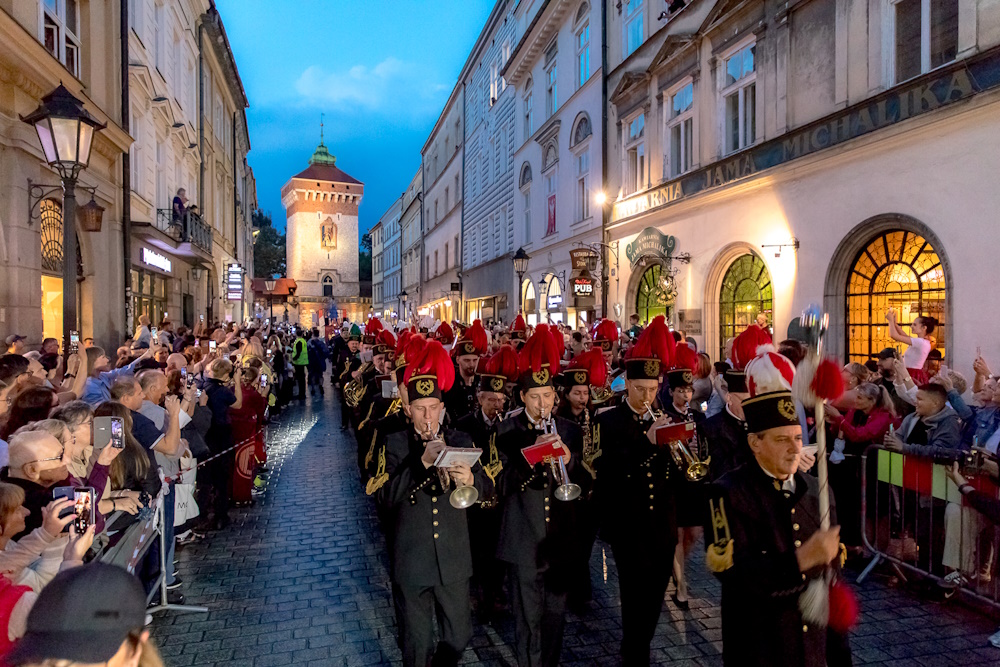 Górnicza orkiestra po zmroku na ulicy Floriańskiej. W tle Brama Floriańska