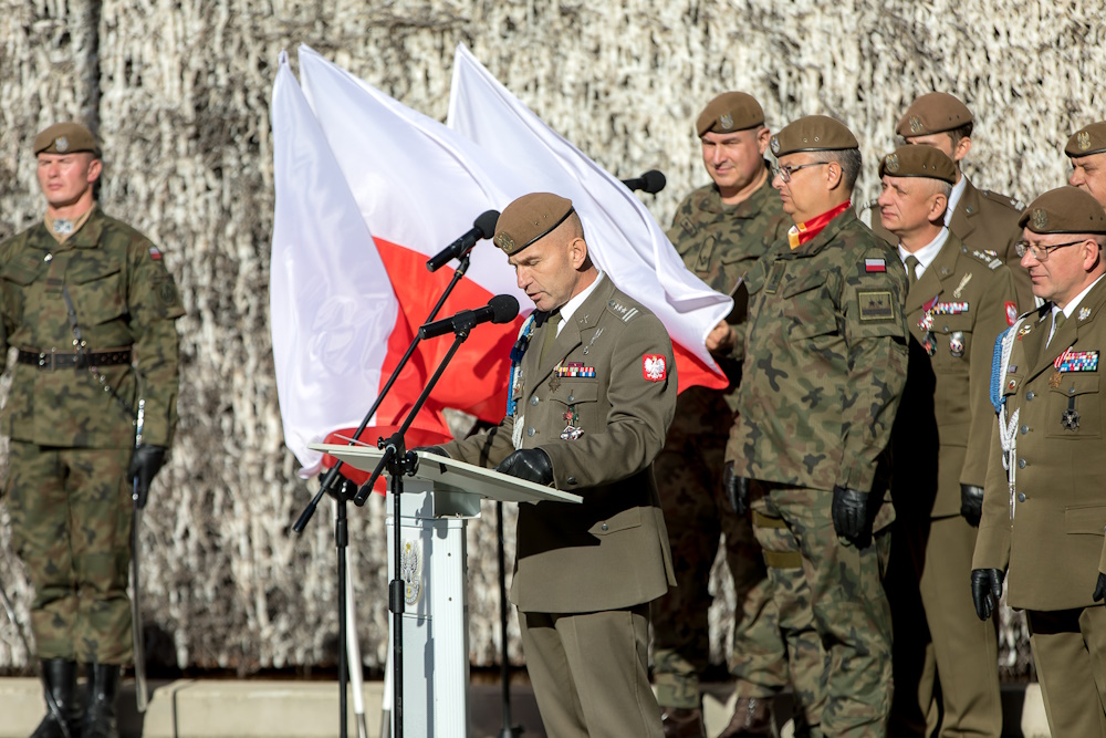 Uczestnicy uroczystości, w tle polskie flagi