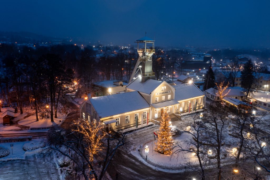 Zimowy nocny widok z lotu ptaka na szyb Daniłowicza. Przed szybem oświetlona choinka