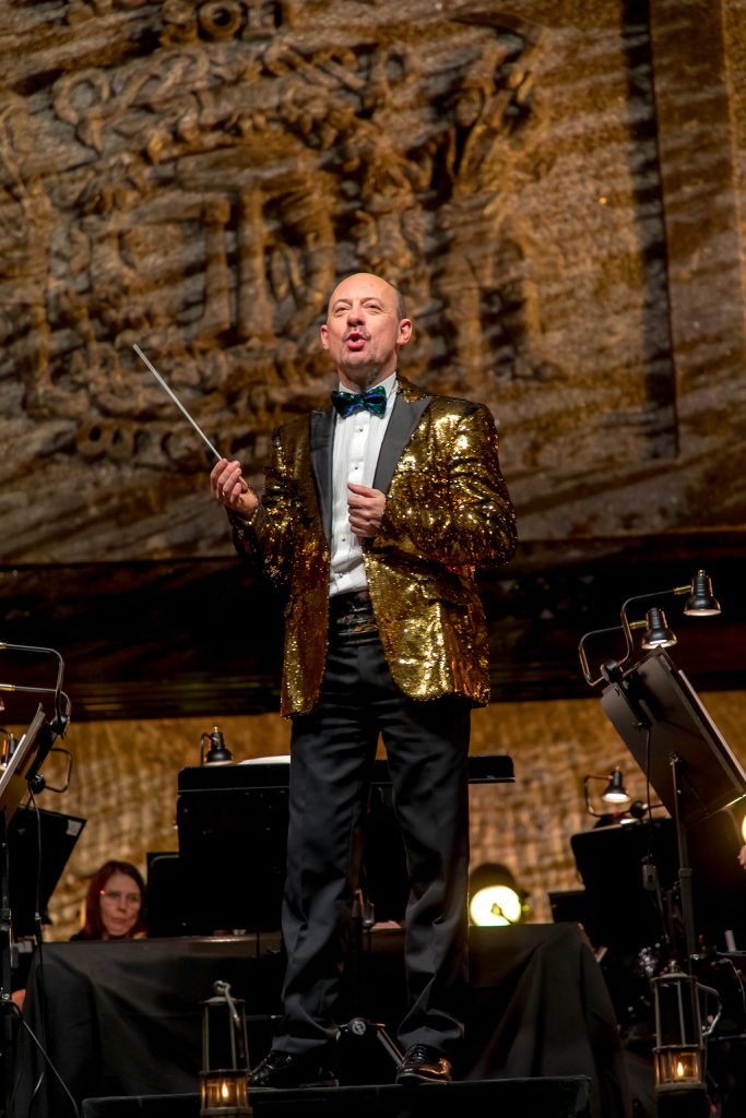 Maestro Piotr Sułkowski z batutą, w charakterystycznej marynarce wyszytej złotymi cekinami