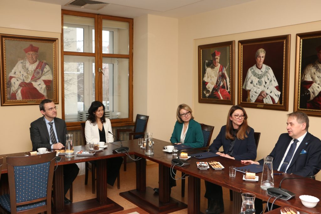 Uczestnicy uroczystego spotkania - wnętrze uniwersyteckie, na ścianie portrety rektorów 