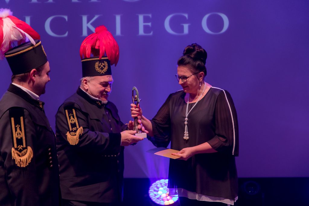 Orkiestranci odbierają nagrodę. Dwaj panowie ubrani w mundury górnicze, w czakach z piórami