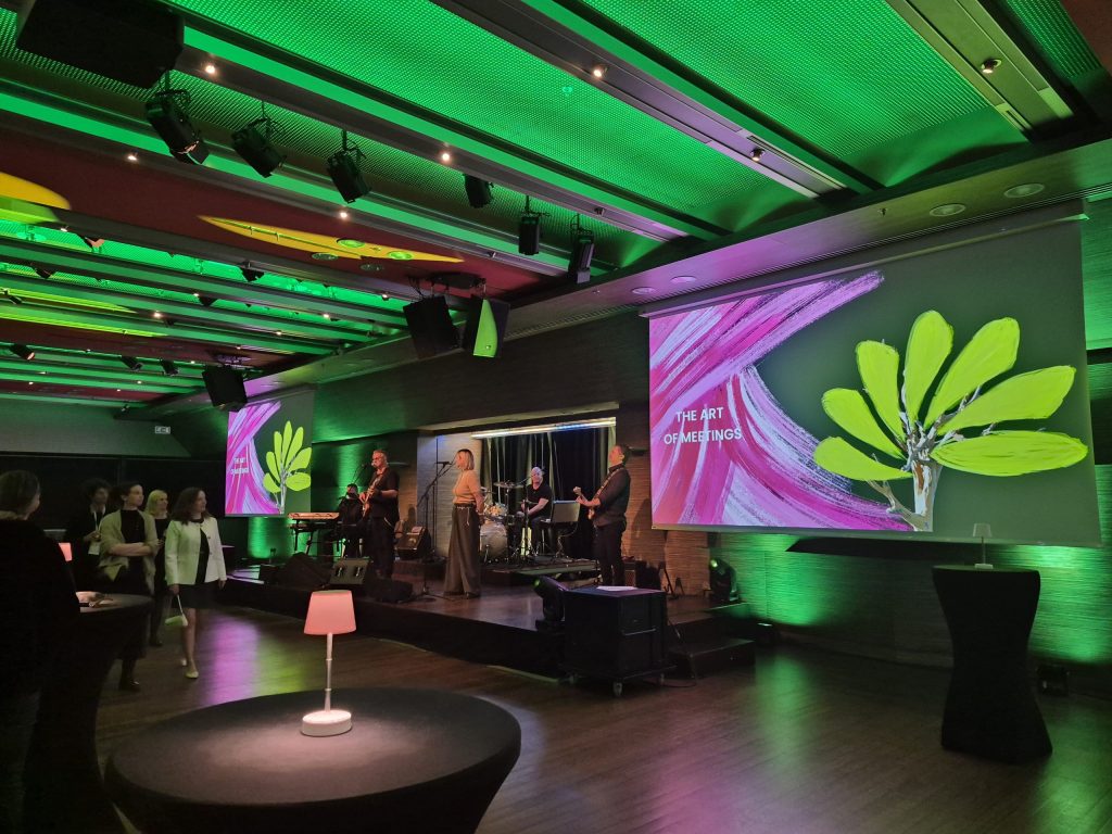 Widok na salę, w której odbyła się gala. Pomieszczenie oświetlone na zielono i fioletowo, w tle ekran