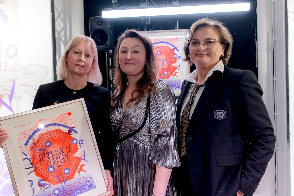 Mariola Kaczor i Agnieszka Wolańska pozują z Dźwigaczem - czerwono-granatowa grafika w ramie