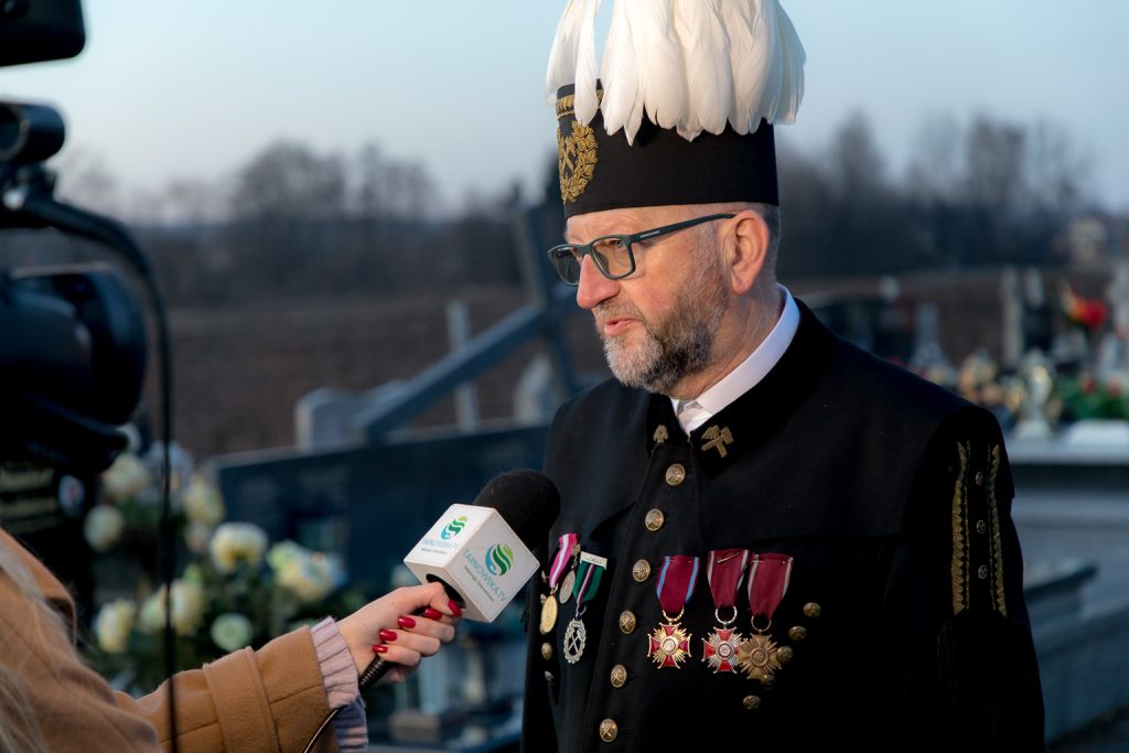 Górnik w czako z białym pióropuszem udziela wywiadu