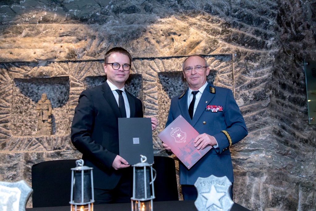 Pamiątkowe zdjęcie. Panowie trzymają w teczkach swoje egzemplarze porozumienia