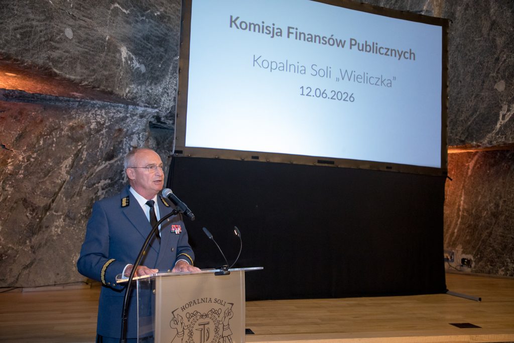 Prezes kopalni Marian Leśny przemawia przy mównicy. W tle ekran z prezentacją