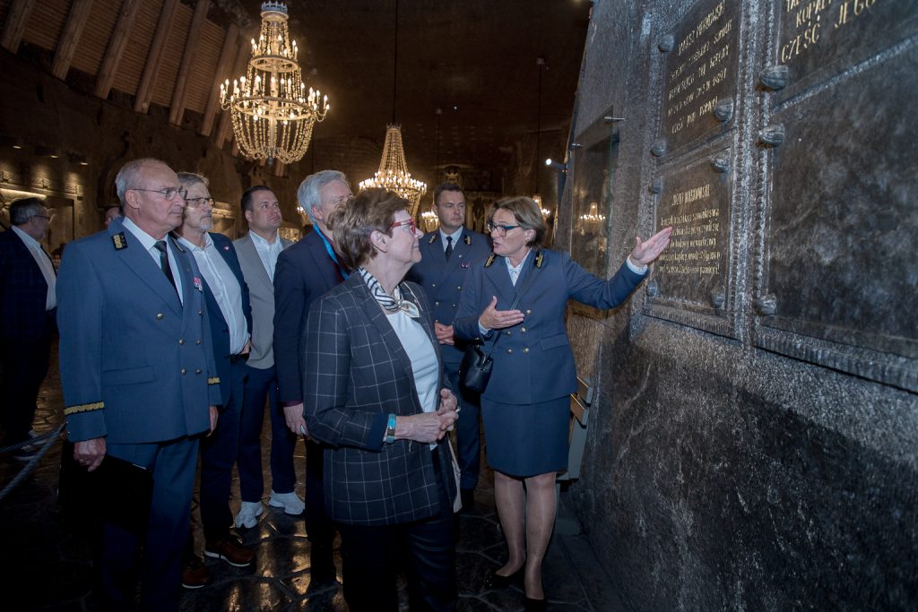 Rzecznik prasowy i pełnomocnik zarządu Agnieszka Wolańska oprowadza członków komisji po kaplicy św. Kingi. Wyciągniętą ręką wskazuje wykute w soli tablice ze złoconymi nazwiskami twórców wystroju świątyni