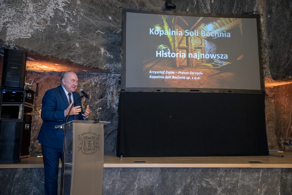 Wystąpienie dyrektora bocheńskiej kopalni. Krzysztof Zięba przy mównicy. W tle ekran z wyświetlaną prezentacją