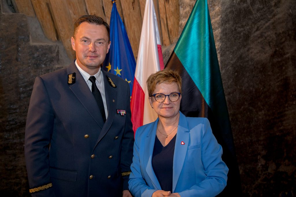 Pamiątkowe zdjęcie: wiceprezes kopalni i członkini komisji. Pani ubrana jest w niebieski żakiet, wiceprezes w szarym mundurze codziennym