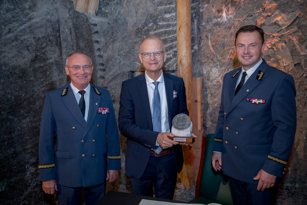Prezesi kopalni oraz prezes WUG Piotr Litwa. W tle solna ściana. Prezes Litwa trzyma w dłoniach pamiątkową solną rzeźbę